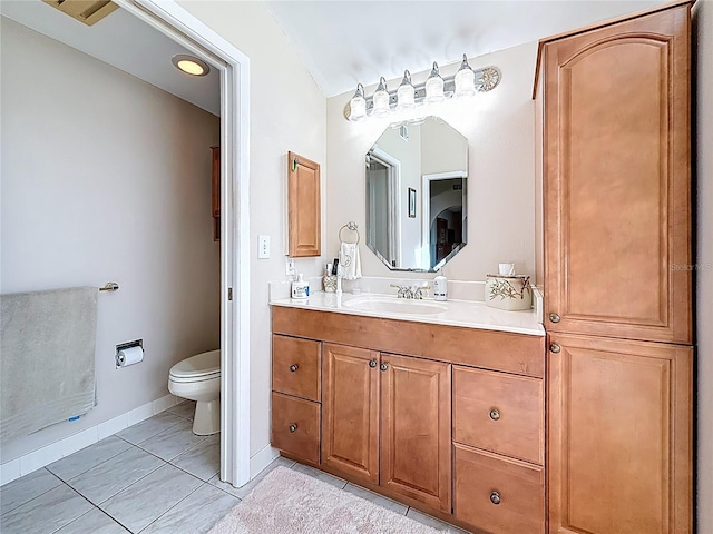 bathroom with toilet, vanity, and baseboards