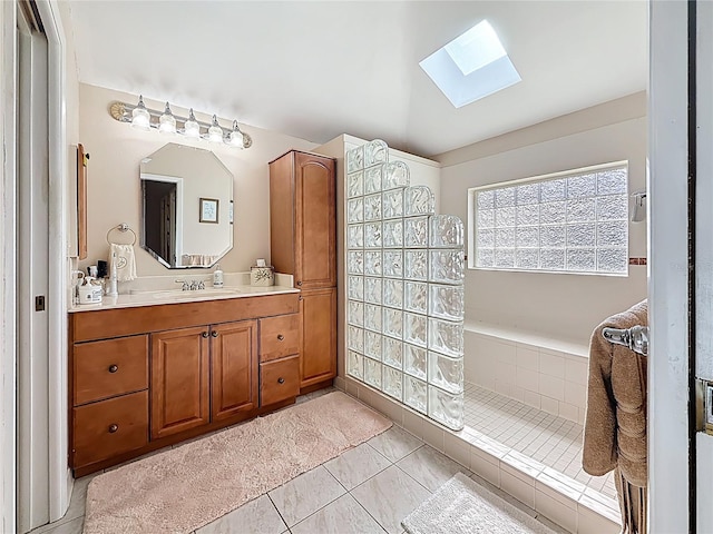 bathroom with vanity, vaulted ceiling with skylight, tile patterned flooring, and walk in shower