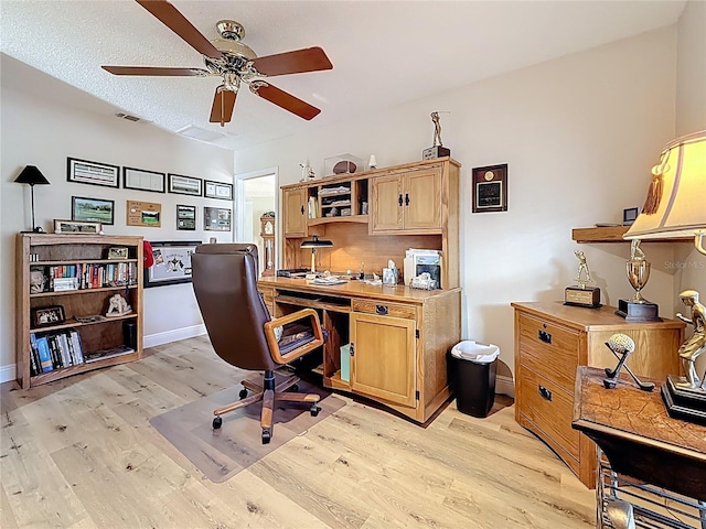 home office with light wood finished floors, baseboards, a textured ceiling, and a ceiling fan