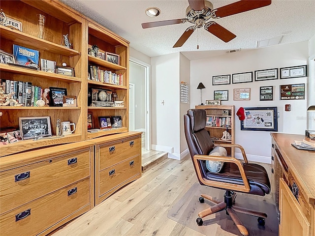 office space with visible vents, a ceiling fan, a textured ceiling, light wood-style floors, and baseboards