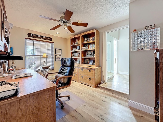 office area featuring baseboards, light wood-style flooring, a textured ceiling, and ceiling fan