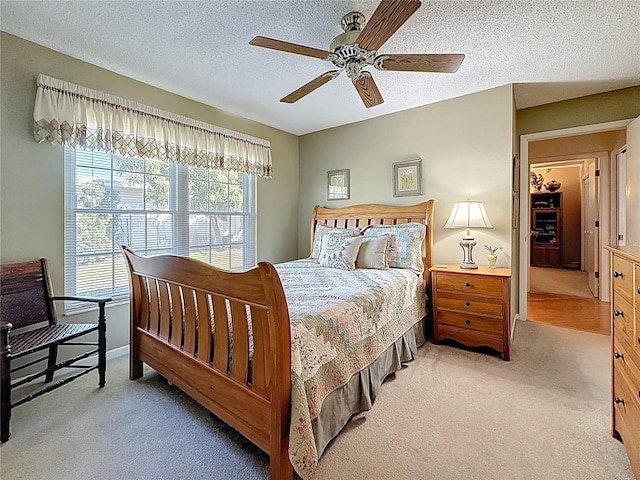 carpeted bedroom featuring ceiling fan and a textured ceiling