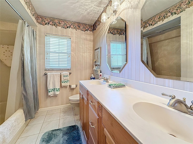 bathroom featuring tile patterned floors, toilet, double vanity, and a sink