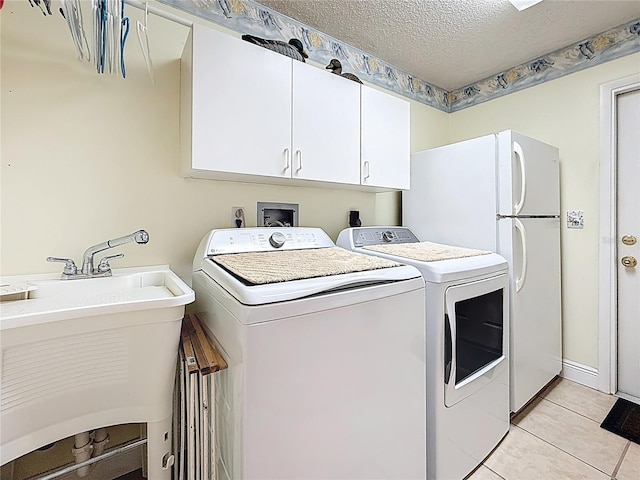 laundry area featuring light tile patterned floors, cabinet space, a sink, a textured ceiling, and washer and clothes dryer