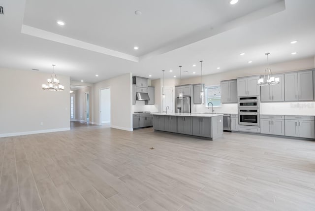 kitchen featuring stainless steel appliances, an inviting chandelier, a sink, gray cabinetry, and open floor plan