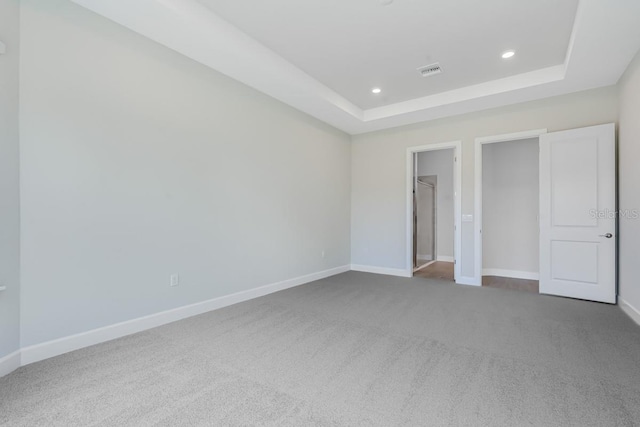 unfurnished bedroom with recessed lighting, a raised ceiling, visible vents, baseboards, and carpet flooring