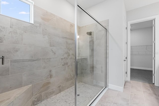 bathroom with baseboards, a spacious closet, and a shower stall
