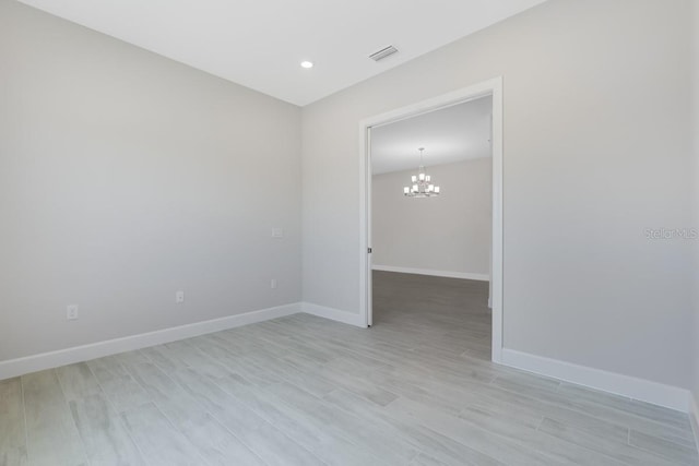 spare room featuring light wood-type flooring, baseboards, visible vents, recessed lighting, and a chandelier
