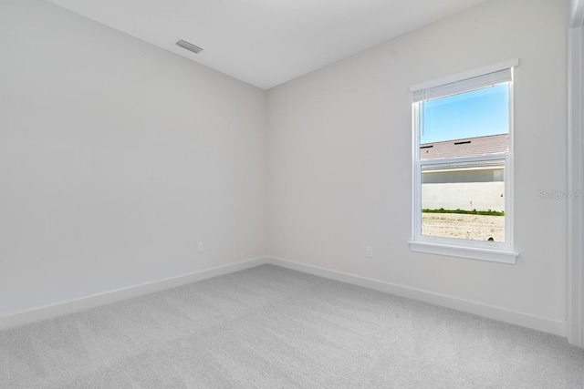 spare room with light carpet, visible vents, and baseboards