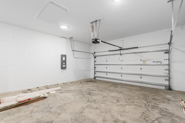 garage featuring concrete block wall, electric panel, and a garage door opener