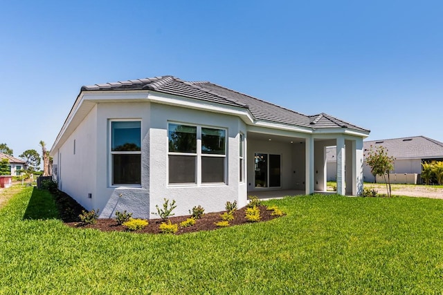 view of front of house with a tiled roof, a front lawn, and stucco siding
