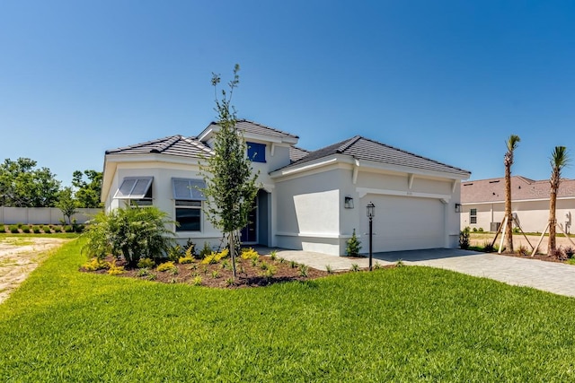 view of front of property with a front lawn, an attached garage, a tiled roof, and stucco siding