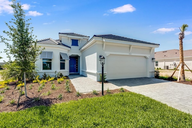 view of front of home with stucco siding, a tile roof, decorative driveway, and a garage