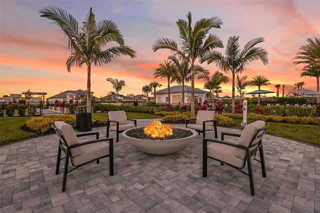 patio terrace at dusk featuring a fire pit and fence