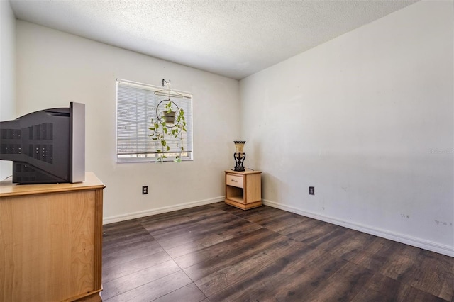 interior space featuring baseboards, a textured ceiling, and dark wood finished floors