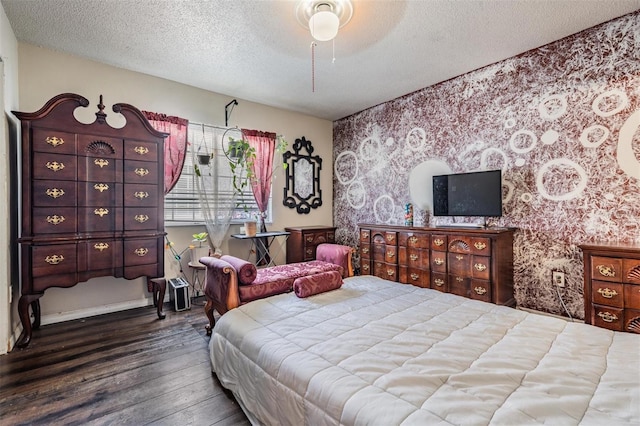 bedroom with wallpapered walls, an accent wall, wood finished floors, a textured ceiling, and a ceiling fan