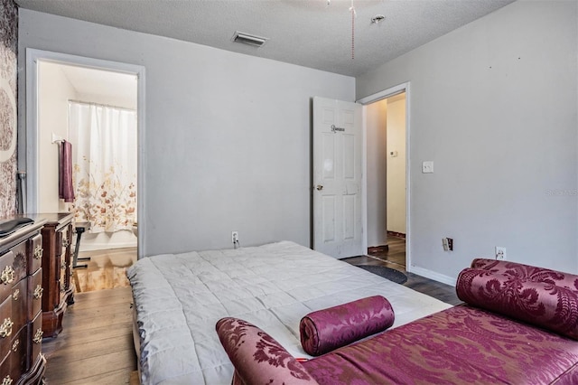 bedroom featuring dark wood finished floors, visible vents, a textured ceiling, and baseboards