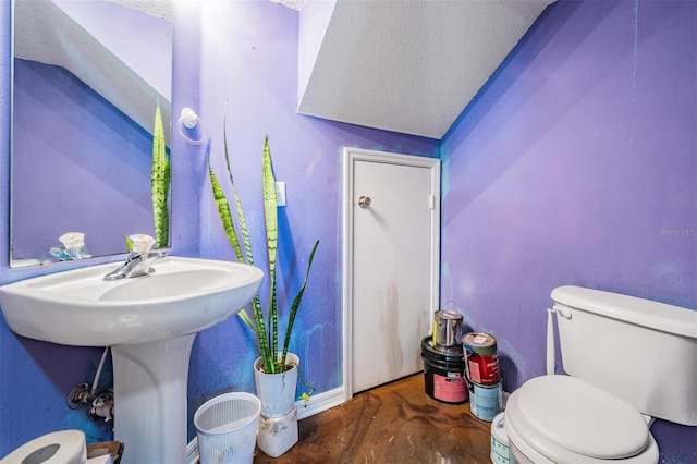 half bath with a textured ceiling, toilet, and wood finished floors