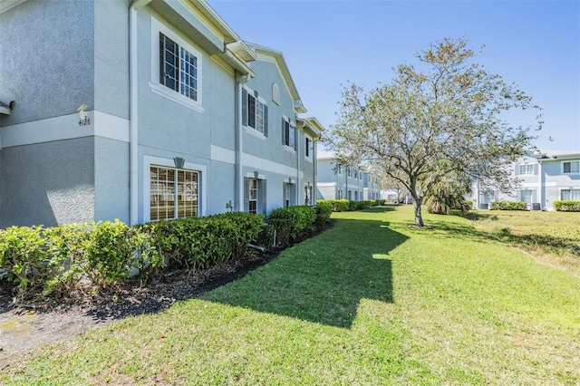 view of side of property featuring stucco siding, a residential view, and a lawn