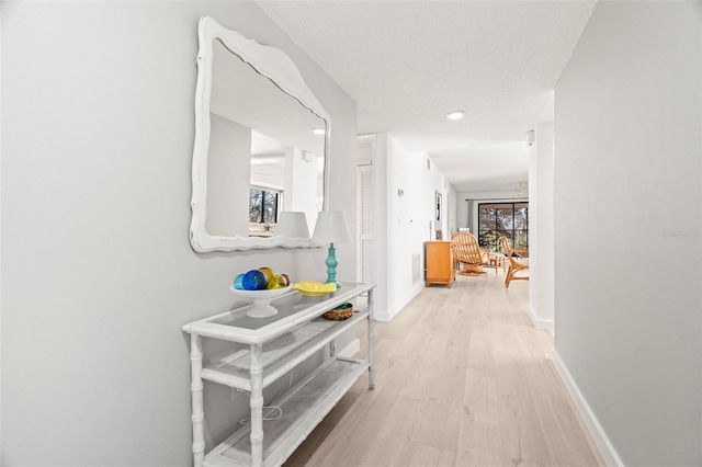 corridor with light wood-type flooring and baseboards