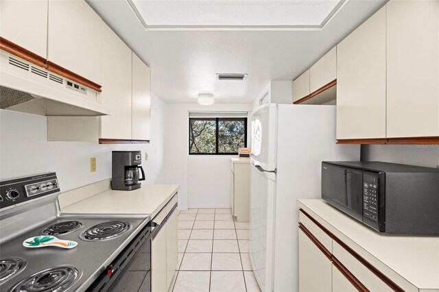 kitchen featuring black microwave, under cabinet range hood, light countertops, range with electric stovetop, and light tile patterned flooring