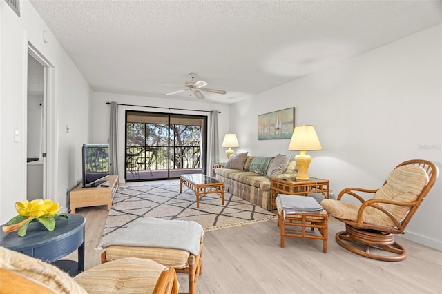 living room with visible vents, a textured ceiling, wood finished floors, baseboards, and ceiling fan