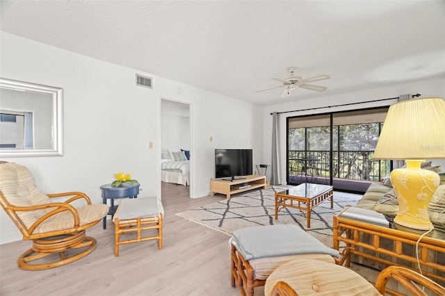 living room with visible vents, a textured ceiling, light wood-type flooring, and ceiling fan