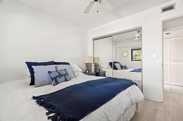 bedroom featuring wood finished floors, visible vents, ceiling fan, a closet, and a textured ceiling