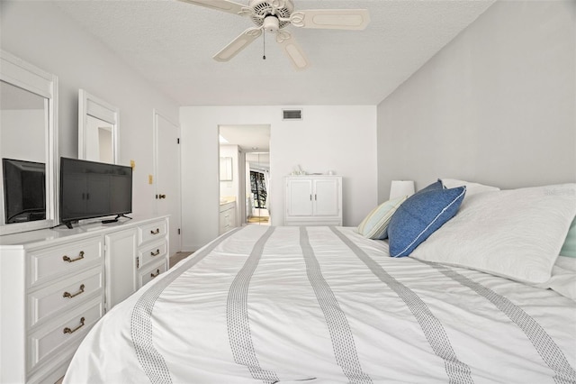 bedroom featuring connected bathroom, visible vents, a textured ceiling, and ceiling fan