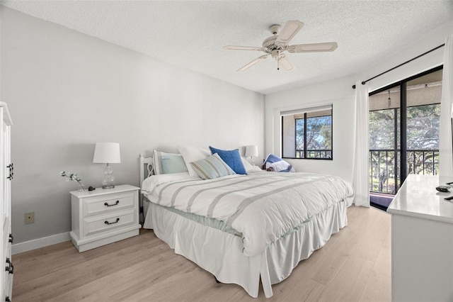 bedroom with access to exterior, baseboards, light wood-type flooring, and a textured ceiling