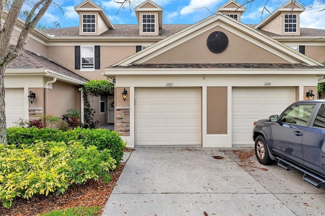 multi unit property with stone siding, stucco siding, concrete driveway, and roof with shingles