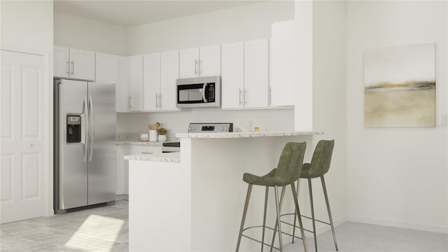 kitchen featuring a breakfast bar area, baseboards, a peninsula, appliances with stainless steel finishes, and white cabinetry