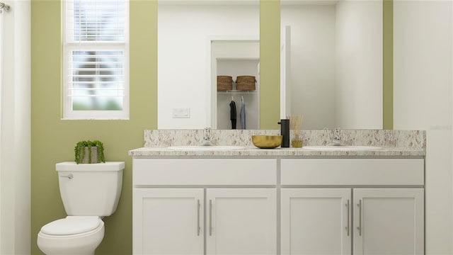 bathroom with double vanity, toilet, and a sink