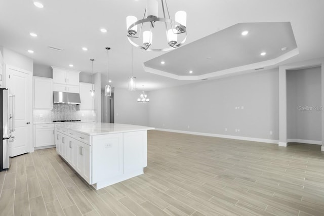 3563 Santa Caterina Blvd, Bradenton, FL 34211 - kitchen featuring under cabinet range hood, a tray ceiling, backsplash, baseboards, and a notable chandelier