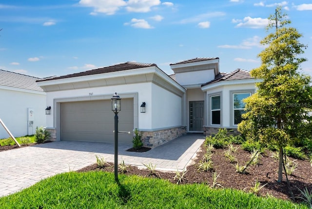 3563 Santa Caterina Blvd, Bradenton, FL 34211 - view of front of home featuring a tiled roof, stucco siding, decorative driveway, stone siding, and a garage