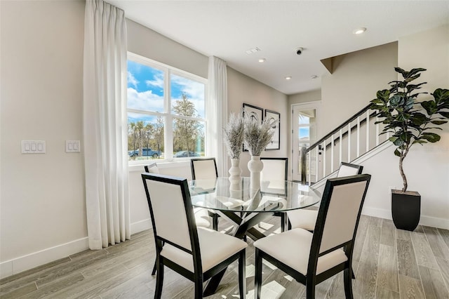 dining space featuring stairs, baseboards, and light wood-type flooring