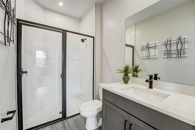 full bath featuring vanity, a shower stall, toilet, and wood finish floors