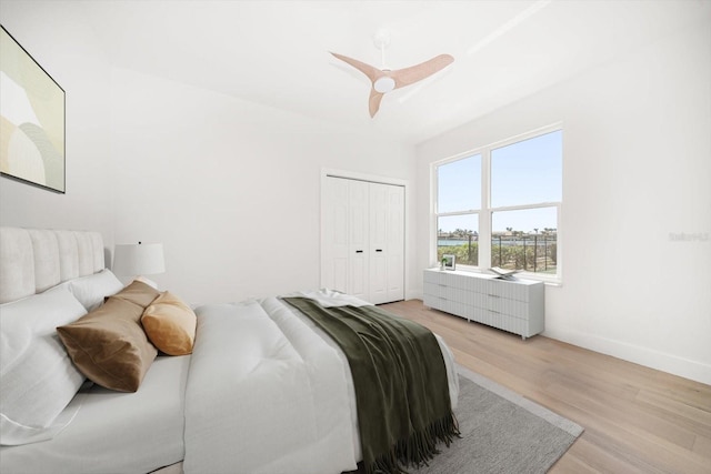 bedroom with a closet, ceiling fan, baseboards, and light wood-style floors