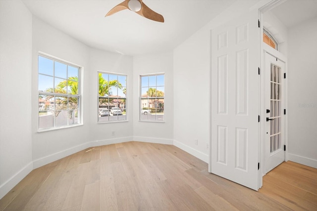 empty room with a ceiling fan, baseboards, and light wood finished floors