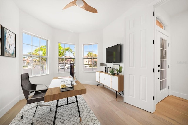 office space featuring baseboards, plenty of natural light, light wood-style floors, and a ceiling fan