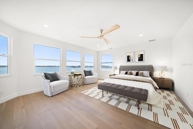 bedroom with wood finished floors, baseboards, a water view, and ceiling fan