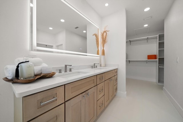 full bath with a sink, a spacious closet, recessed lighting, and double vanity