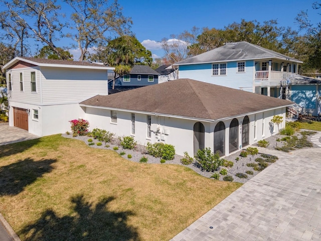 exterior space featuring stucco siding, decorative driveway, and a yard