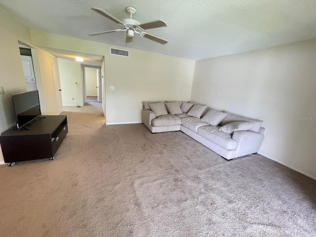 carpeted living room with visible vents, baseboards, a textured ceiling, and a ceiling fan