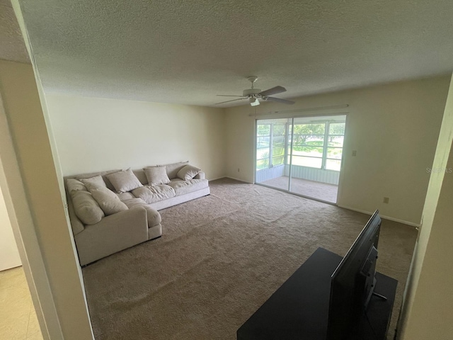 living room with baseboards, carpet floors, a textured ceiling, and ceiling fan