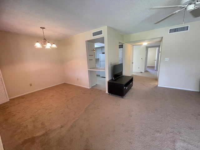 unfurnished living room featuring visible vents, ceiling fan with notable chandelier, a textured ceiling, and carpet