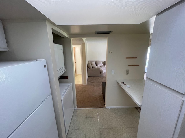 laundry room with visible vents, baseboards, stacked washer and dryer, and light floors