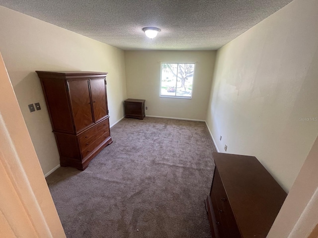 unfurnished bedroom with light colored carpet, a textured ceiling, and baseboards