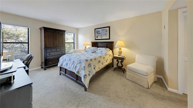 bedroom with light colored carpet and baseboards