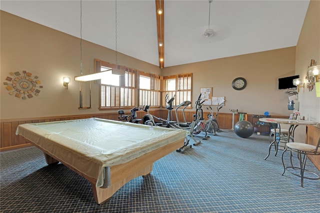 rec room with wooden walls, carpet flooring, a wainscoted wall, and high vaulted ceiling